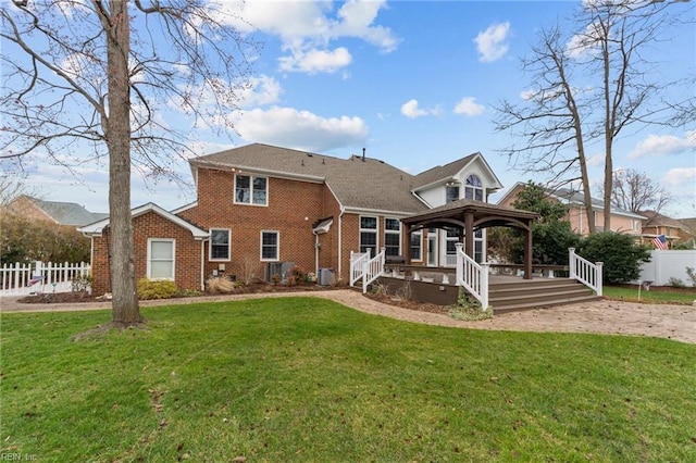 back of property featuring a gazebo, fence, a lawn, and brick siding