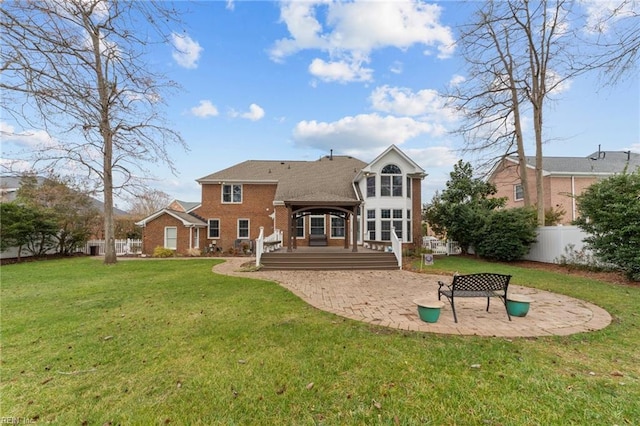 back of property with a patio, a fenced backyard, a deck, a yard, and brick siding