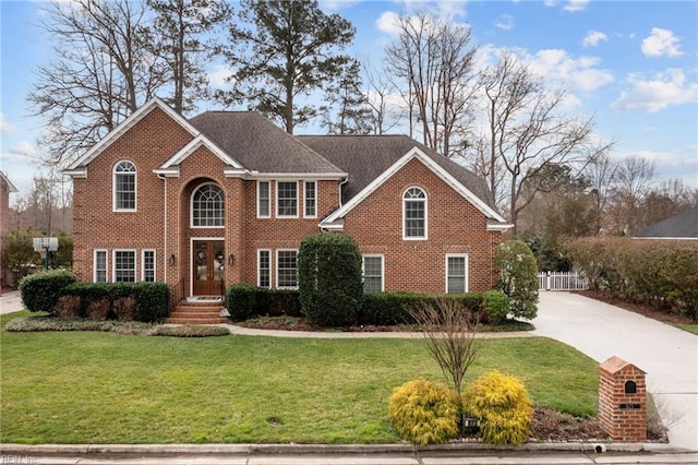 view of front of home featuring driveway, a front lawn, fence, and brick siding