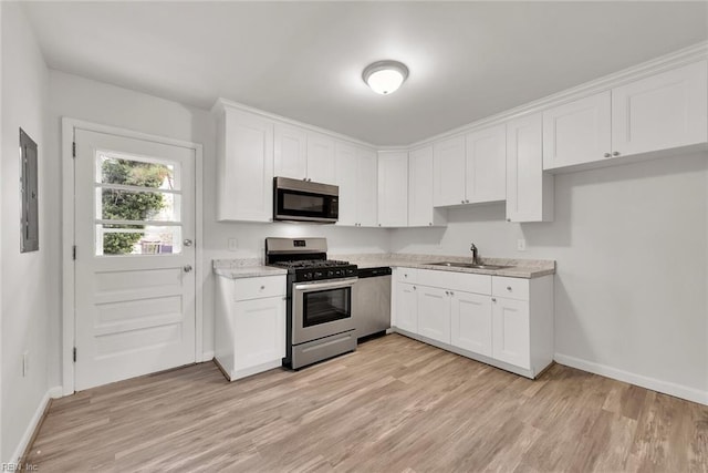 kitchen with stainless steel appliances, white cabinetry, a sink, light wood-type flooring, and electric panel