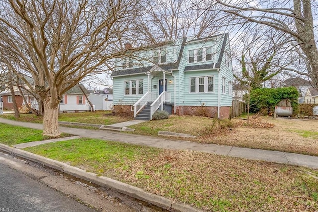 view of front of home with roof with shingles and a front yard