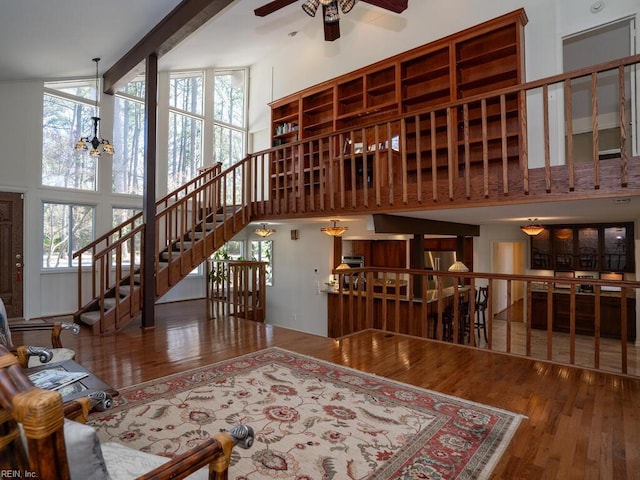 living room featuring ceiling fan with notable chandelier, hardwood / wood-style floors, and a towering ceiling