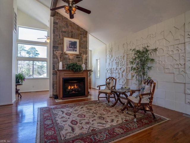 living area featuring ceiling fan, high vaulted ceiling, a fireplace, and wood finished floors