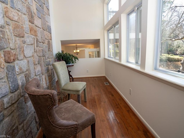 living area with wood-type flooring, visible vents, a notable chandelier, and baseboards