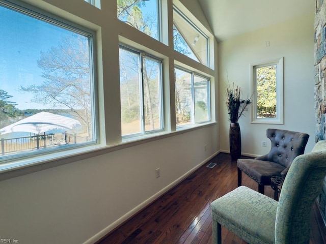 living area with baseboards, visible vents, dark wood-type flooring, and a wealth of natural light