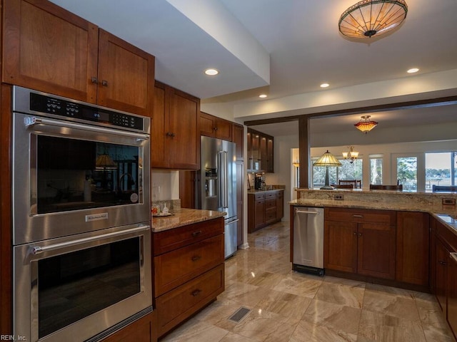 kitchen with a chandelier, appliances with stainless steel finishes, recessed lighting, and light stone countertops