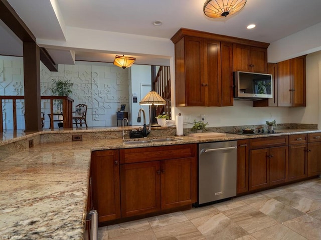 kitchen featuring a sink, appliances with stainless steel finishes, brown cabinetry, and light stone counters