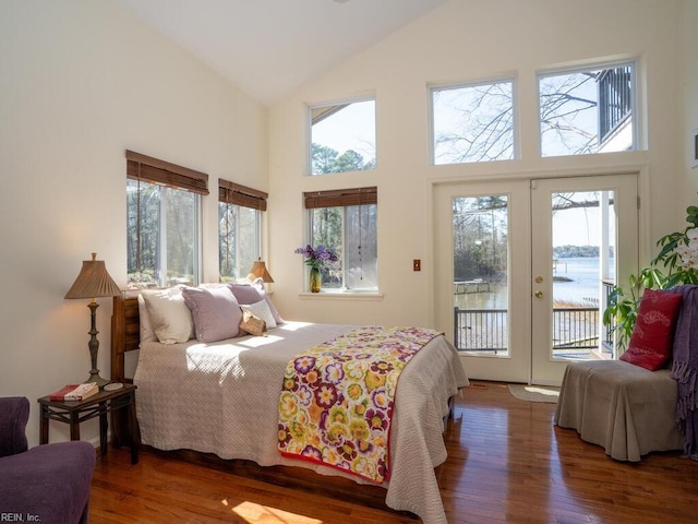 bedroom with access to outside, high vaulted ceiling, wood finished floors, and french doors