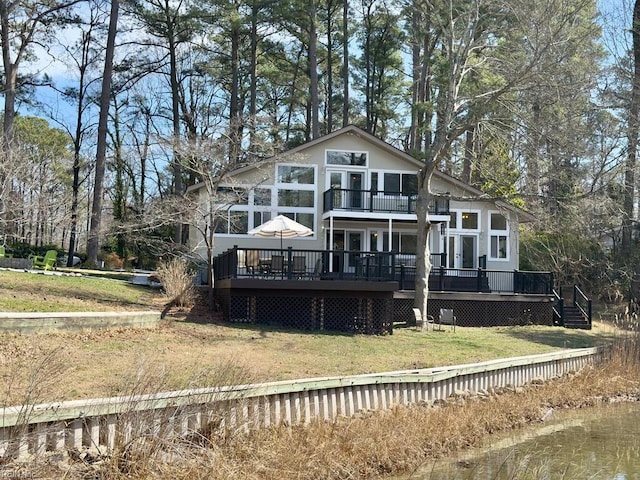 back of property featuring a deck, a lawn, and a balcony