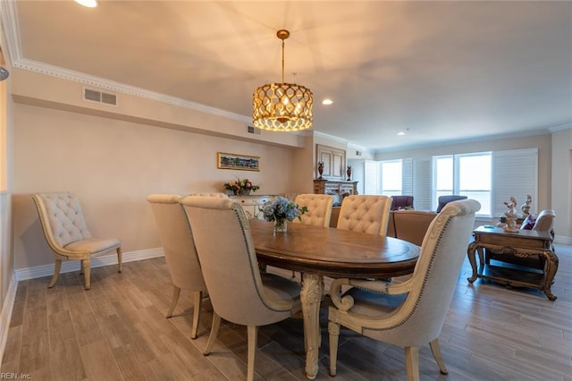 dining area featuring ornamental molding, visible vents, light wood-style flooring, and baseboards