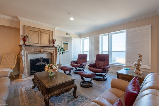 living room featuring a premium fireplace, wood finished floors, visible vents, baseboards, and ornamental molding