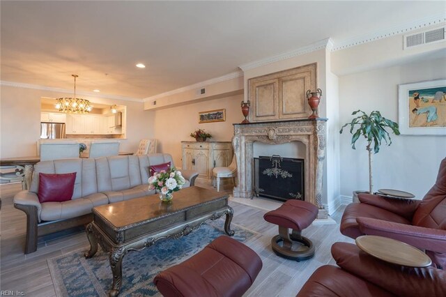 living area featuring light wood finished floors, visible vents, ornamental molding, an inviting chandelier, and a high end fireplace