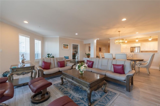 living room with an inviting chandelier, light wood-style flooring, and crown molding