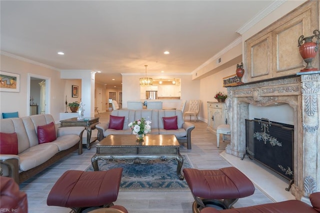 living room with a fireplace with raised hearth, light wood finished floors, recessed lighting, and crown molding