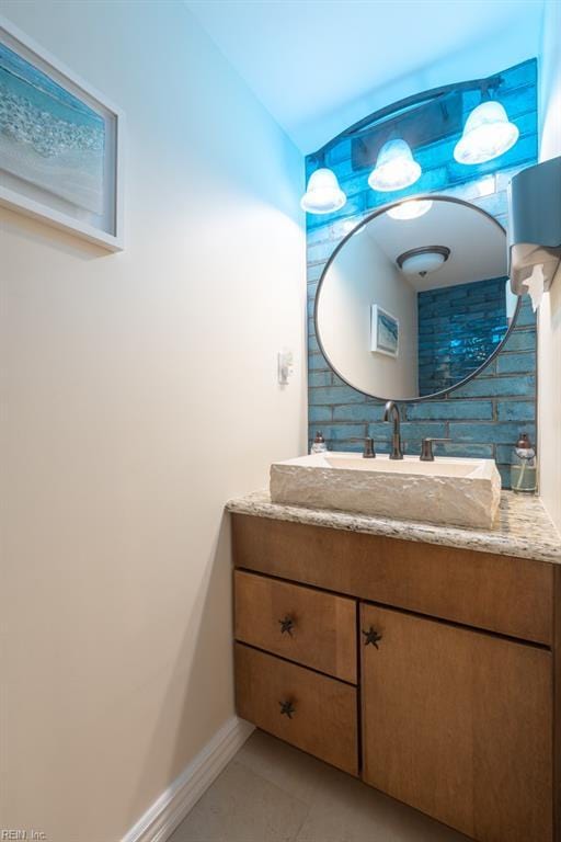 bathroom featuring decorative backsplash, vanity, baseboards, and tile patterned floors