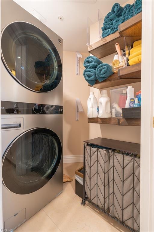 washroom with laundry area, tile patterned flooring, baseboards, and stacked washer / dryer