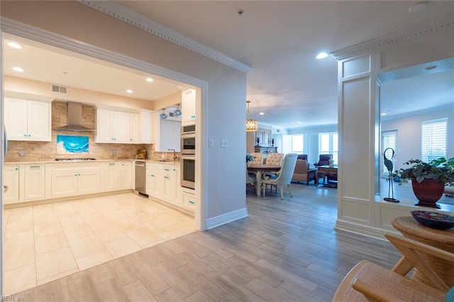 kitchen featuring light wood-style flooring, stainless steel appliances, open floor plan, wall chimney range hood, and decorative backsplash