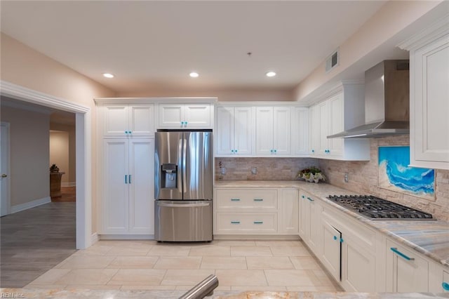 kitchen featuring appliances with stainless steel finishes, white cabinets, and wall chimney exhaust hood