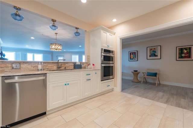 kitchen with tasteful backsplash, white cabinets, appliances with stainless steel finishes, a sink, and recessed lighting