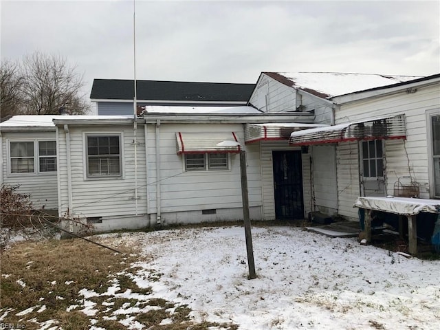 snow covered rear of property with crawl space