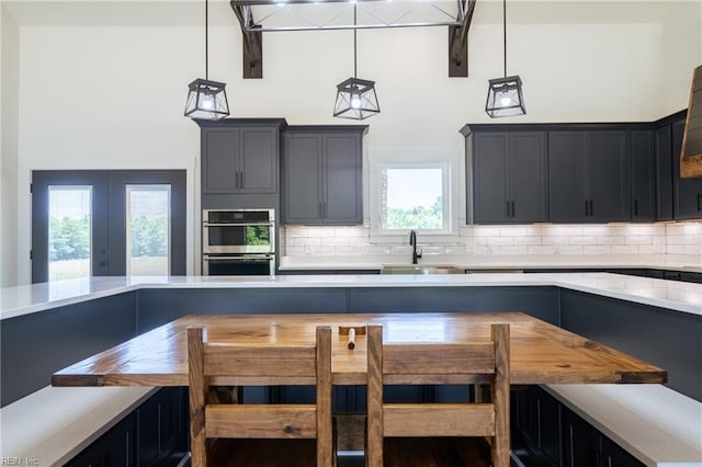 kitchen featuring a sink, a towering ceiling, light countertops, backsplash, and breakfast area