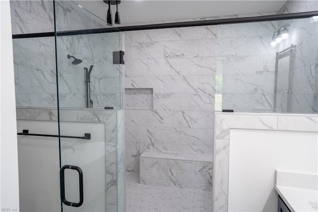 full bathroom with a marble finish shower and vanity