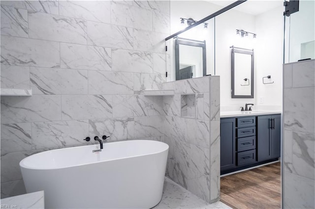 bathroom featuring wood finished floors, a freestanding tub, and vanity