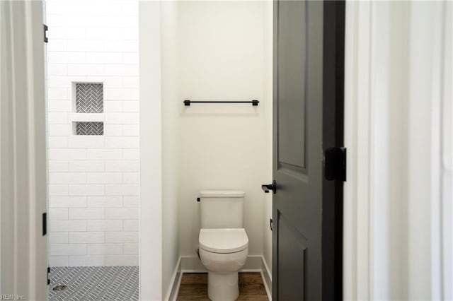 full bathroom featuring toilet, a shower stall, and baseboards