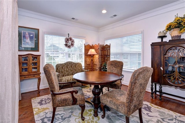 dining area with baseboards, visible vents, ornamental molding, and wood finished floors