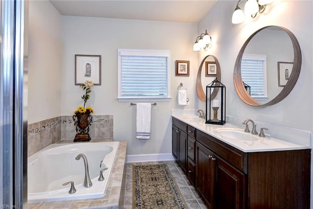 full bath featuring a garden tub, double vanity, a sink, and baseboards