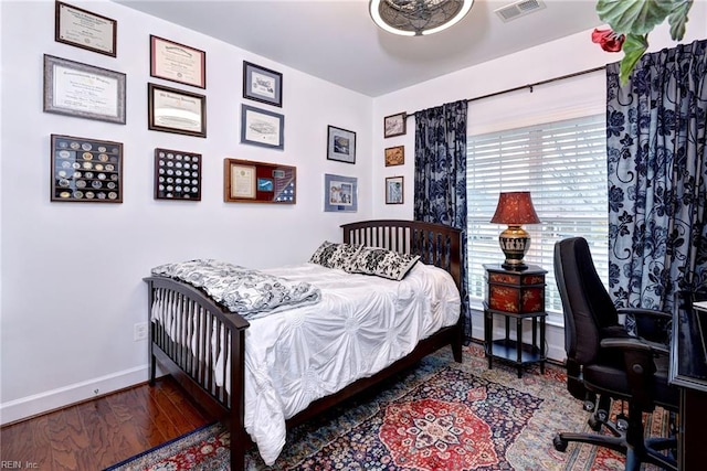 bedroom featuring wood finished floors, visible vents, and baseboards