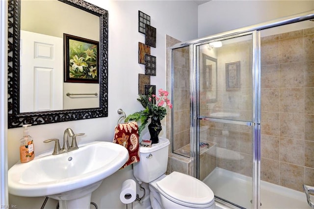 bathroom featuring a stall shower, a sink, and toilet