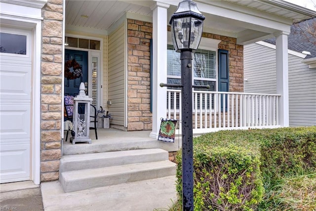 property entrance with stone siding, covered porch, and a garage