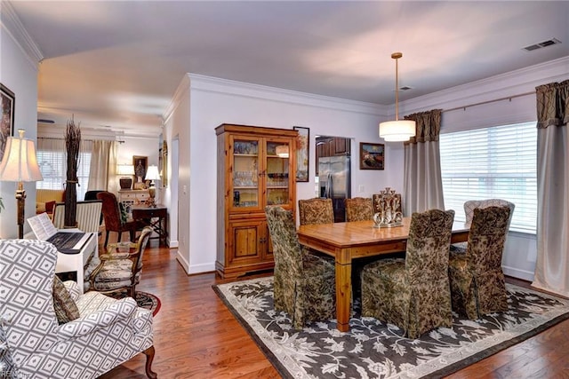 dining area with baseboards, visible vents, wood finished floors, and ornamental molding