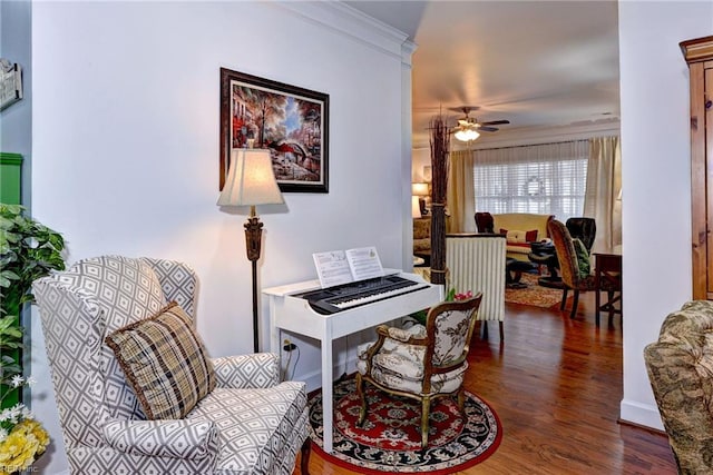 living area featuring ceiling fan, baseboards, wood finished floors, and crown molding