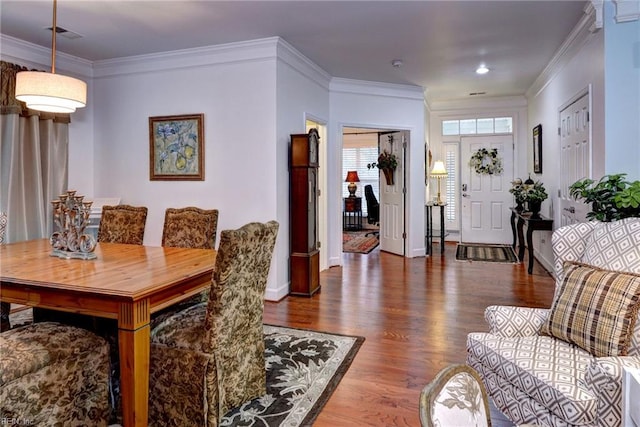 dining area featuring visible vents, crown molding, baseboards, and wood finished floors