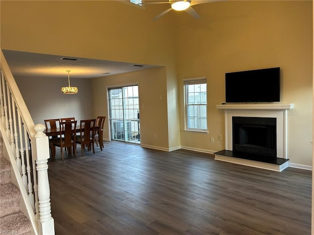 unfurnished living room with dark wood-style floors, a fireplace with raised hearth, stairway, and baseboards