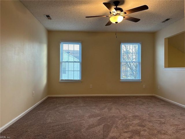 carpeted spare room with visible vents, a textured ceiling, and baseboards