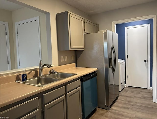 kitchen with light countertops, light wood-style floors, a sink, washer and dryer, and dishwasher