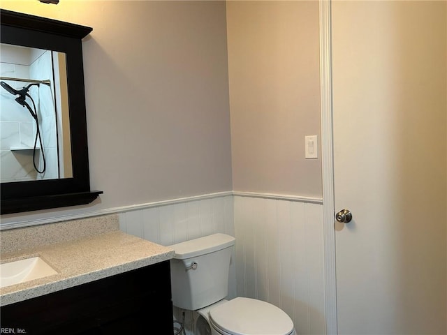 bathroom featuring toilet, wainscoting, and vanity