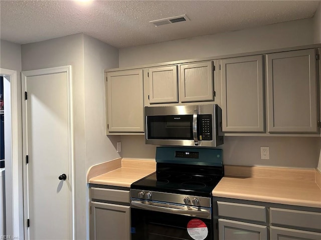 kitchen with visible vents, stainless steel appliances, light countertops, and gray cabinetry