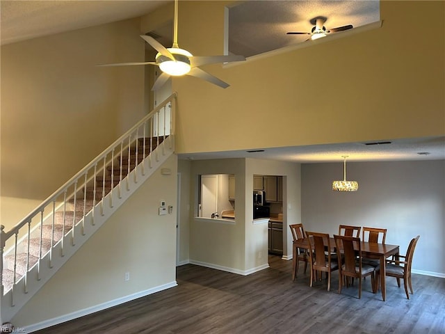 dining room with ceiling fan with notable chandelier, dark wood finished floors, baseboards, and stairs