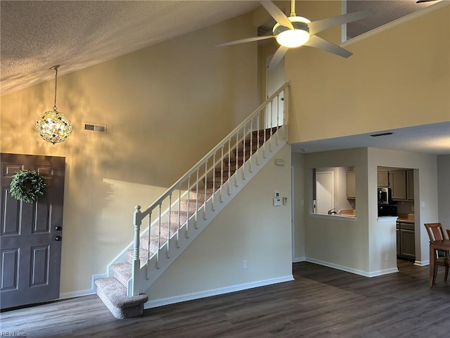 entrance foyer with high vaulted ceiling, baseboards, stairway, and dark wood-type flooring