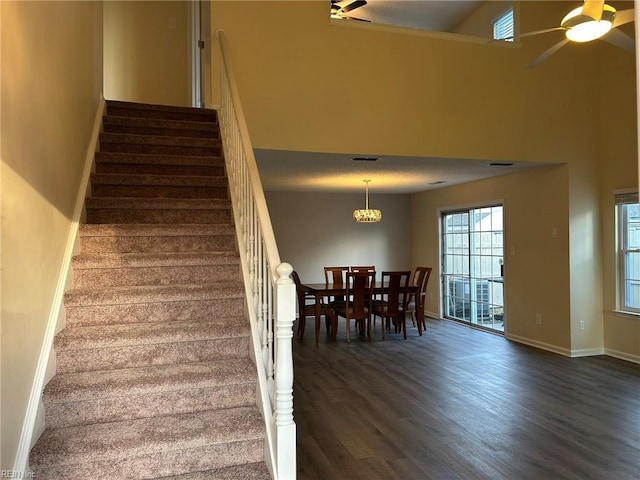 staircase featuring a textured ceiling, wood finished floors, a ceiling fan, and baseboards