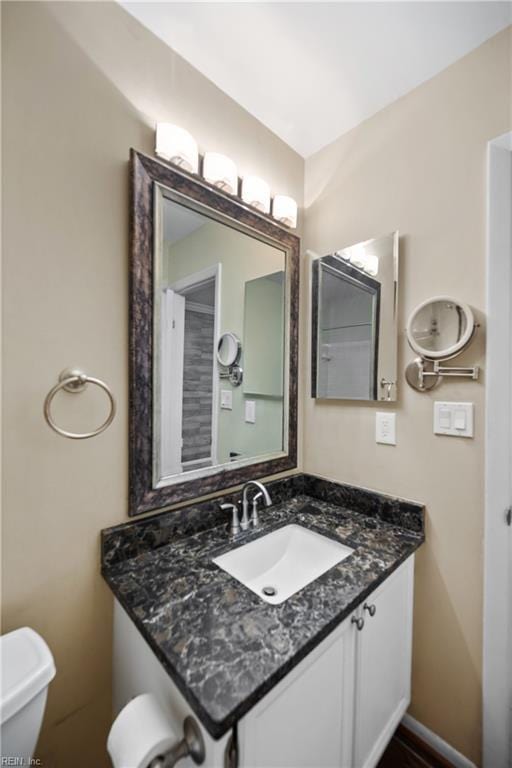 half bathroom featuring vanity, toilet, and baseboards