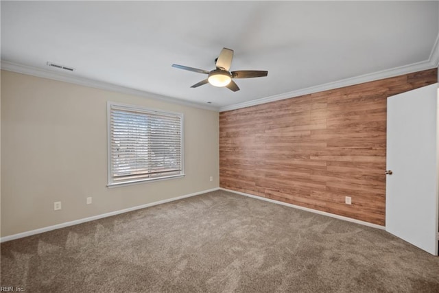 carpeted empty room featuring wood walls, visible vents, and crown molding