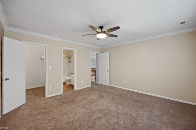 unfurnished bedroom with ornamental molding, carpet floors, a spacious closet, and baseboards