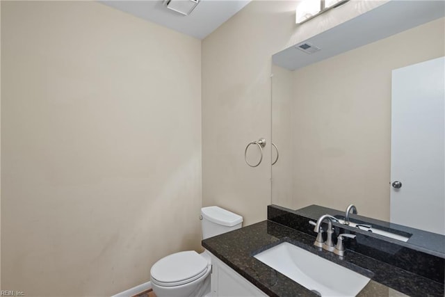 half bathroom with visible vents, vanity, and toilet