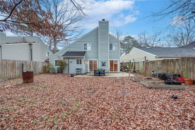 rear view of house with a chimney, a patio area, and a fenced backyard