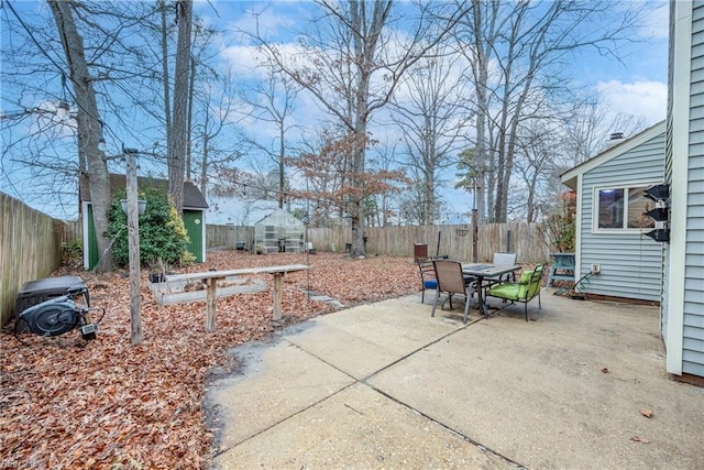 view of patio / terrace with outdoor dining space, a fenced backyard, and an outbuilding